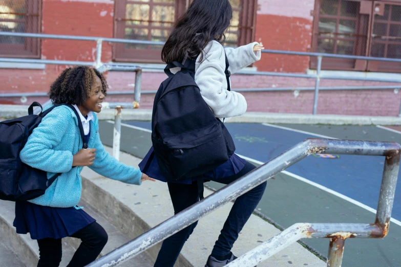 two young girls walking up a set of stairs, pexels contest winner, american barbizon school, a backpack, black teenage girl, reaching out to each other, urban playground