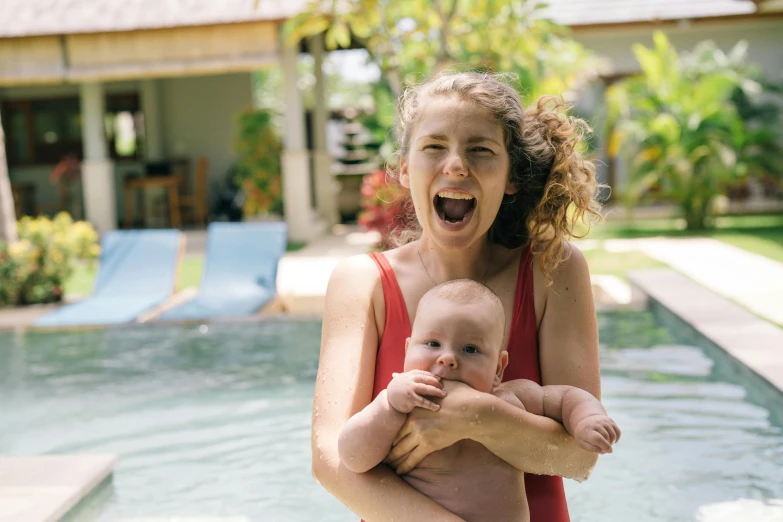 a woman holding a baby in front of a pool, pexels contest winner, happening, wide open mouth in terror, bali, avatar image, caspar david