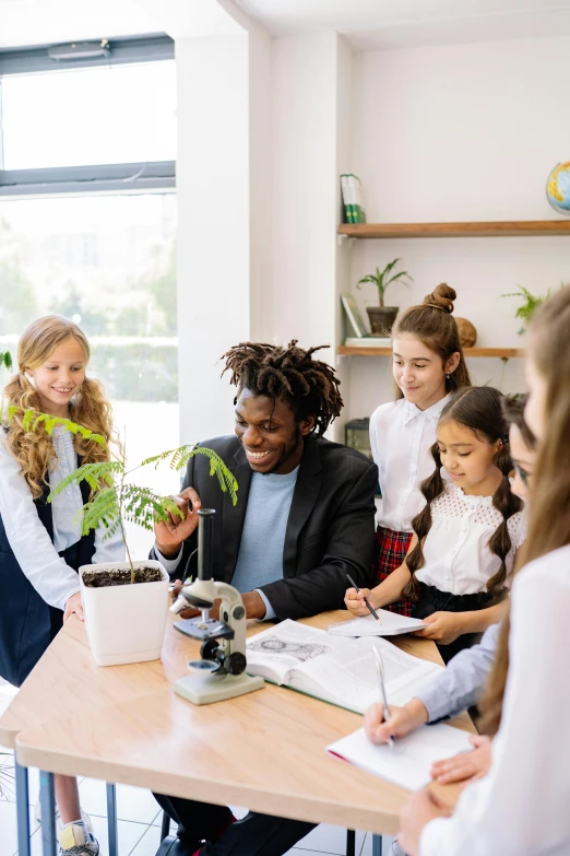 a group of children sitting around a table in a classroom, pexels contest winner, next to a plant, teaching, unedited, promotional image