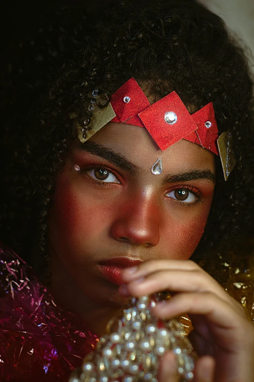 a close up of a person wearing a costume, afrofuturism, portrait of modern darna, wearing a paper crown, arabian nights inspired, red magic surrounds her
