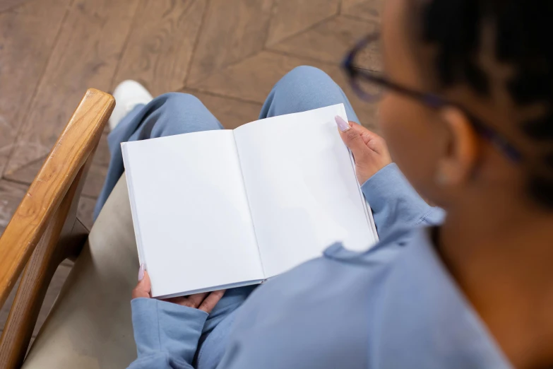 a woman sitting in a chair reading a book, a sketch, happening, nurse scrubs, high angle close up shot, no - text no - logo, thumbnail