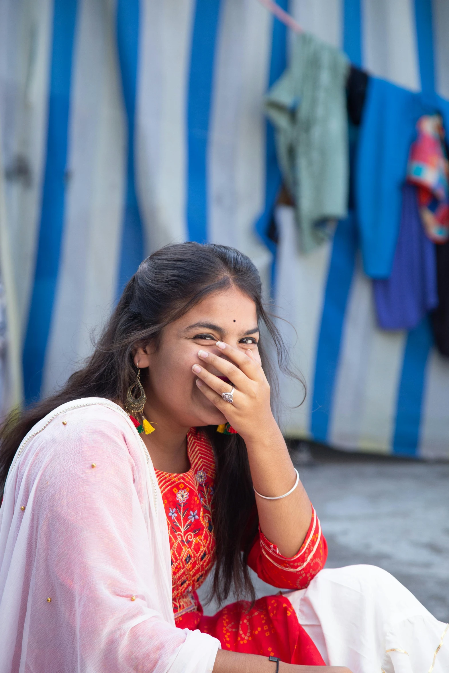 a woman sitting on the ground talking on a cell phone, pexels contest winner, young himalayan woman, earing a shirt laughing, shy, dressed in a sari