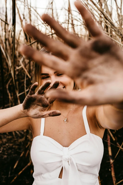 a woman making a stop sign with her hands, by Lucia Peka, trending on pexels, happening, photoshoot for skincare brand, in nature, dirt - stained skin, close up of a blonde woman