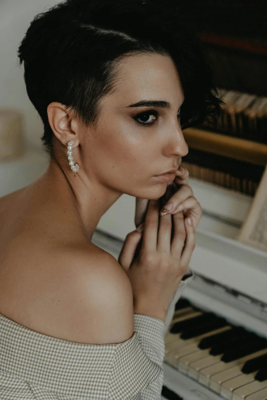 a woman sitting in front of a piano, inspired by Elsa Bleda, trending on pexels, baroque, pixie cut with shaved side hair, girl with a pearl earringl, accentuated feminine features, blanca alvarez