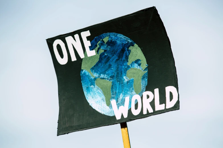 a person holding a sign that says one world, an album cover, by Julia Pishtar, trending on unsplash, renaissance, green flags, blue marble, steam workshop, protest