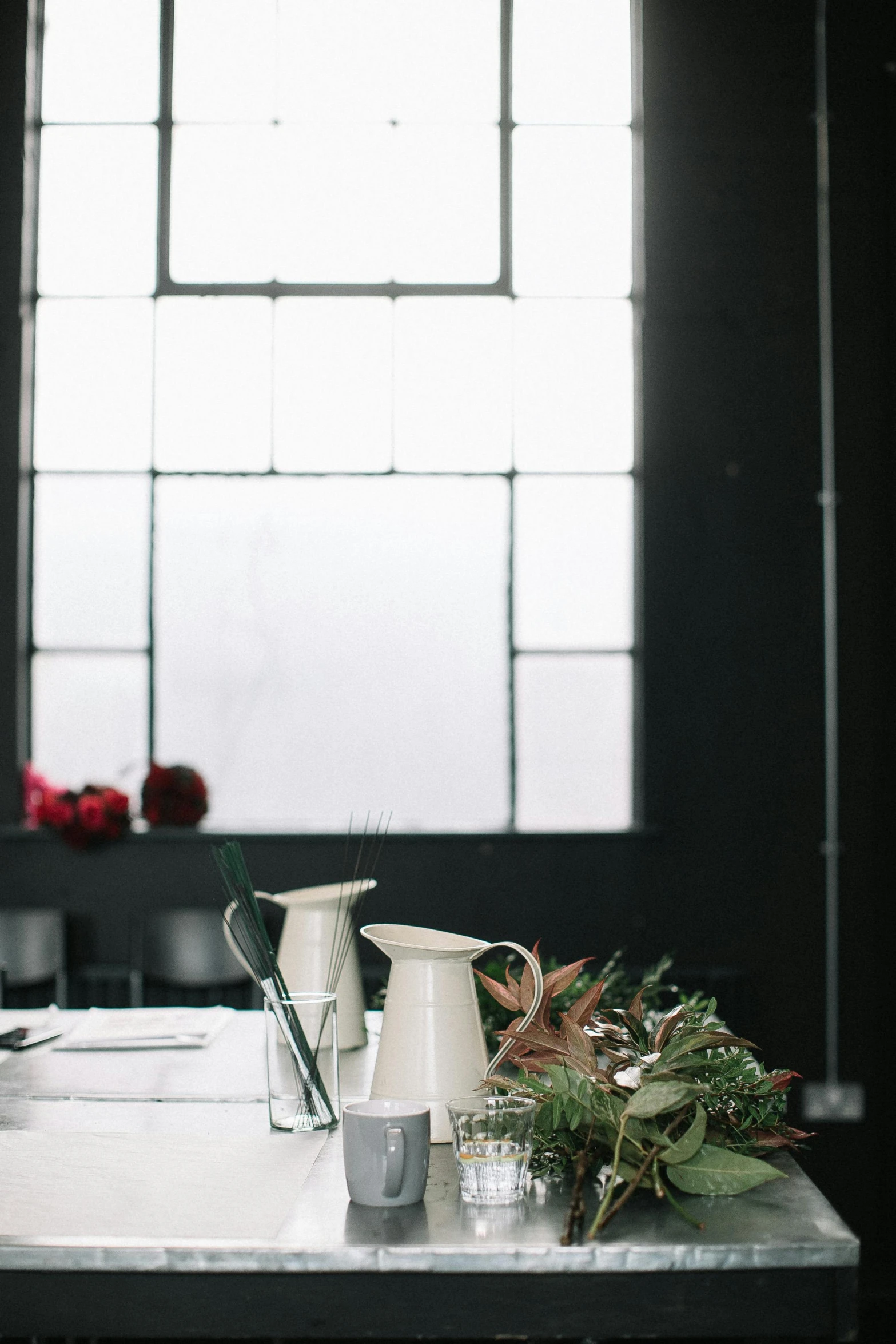 a table topped with a vase of flowers next to a window, unsplash, light and space, chefs table, white on black, industrial aesthetic, ready for a meeting