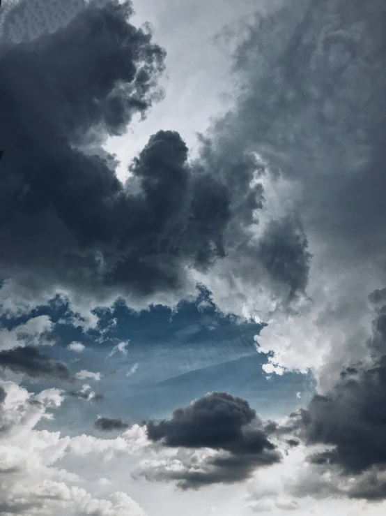 a group of people standing on top of a beach under a cloudy sky, a picture, unsplash contest winner, romanticism, dark mammatus cloud, ☁🌪🌙👩🏾, blue and gray colors, looking up onto the sky