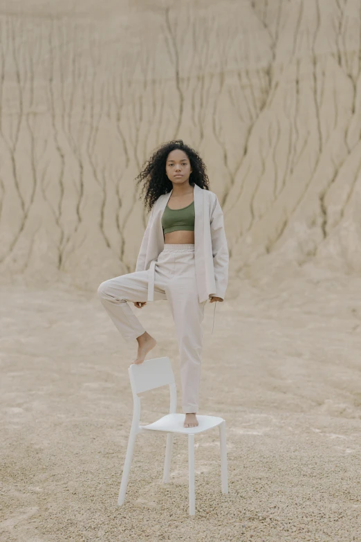 a woman standing on top of a white chair, trending on pexels, renaissance, wearing a track suit, covered in sand, sydney park, physical : tinyest midriff ever