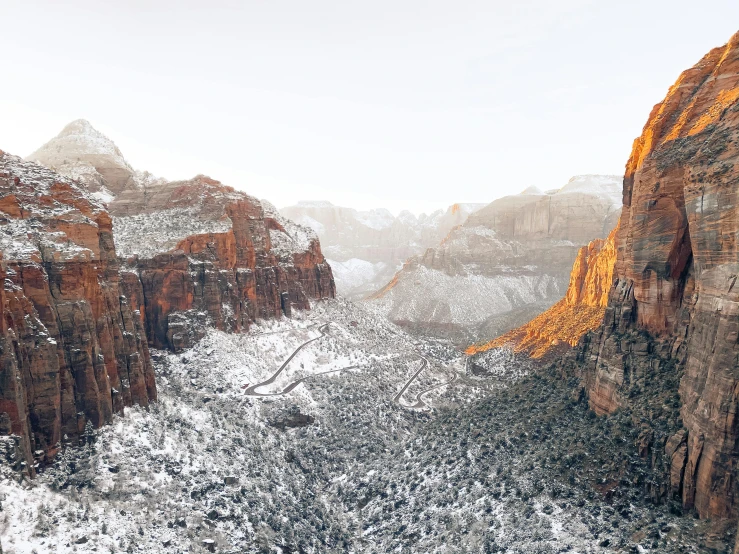 a view of a snowy canyon from the top of a mountain, a matte painting, unsplash contest winner, sheer cliffs surround the scene, brightly lit, 2000s photo, utah