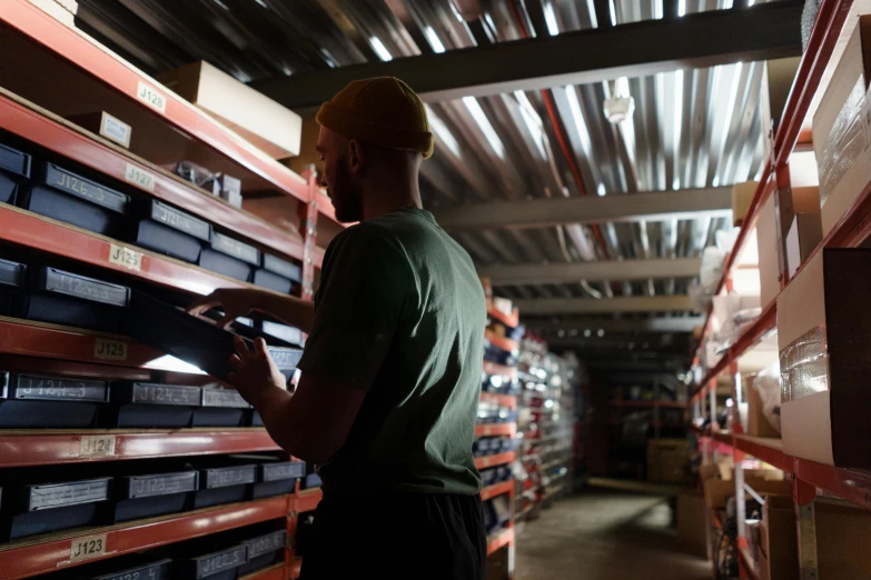 a man standing in front of a wall of boxes, inspect in inventory image, thumbnail, low lighting, worksafe. cinematic