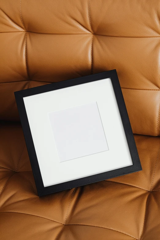 a picture frame sitting on top of a leather couch, by Harvey Quaytman, unsplash, square shapes, matte black paper, royal photo, small