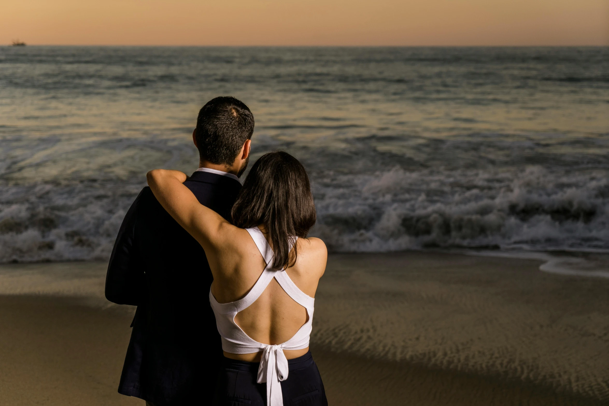 a man and a woman standing on top of a beach, in the evening, profile image, facing away from camera, manly
