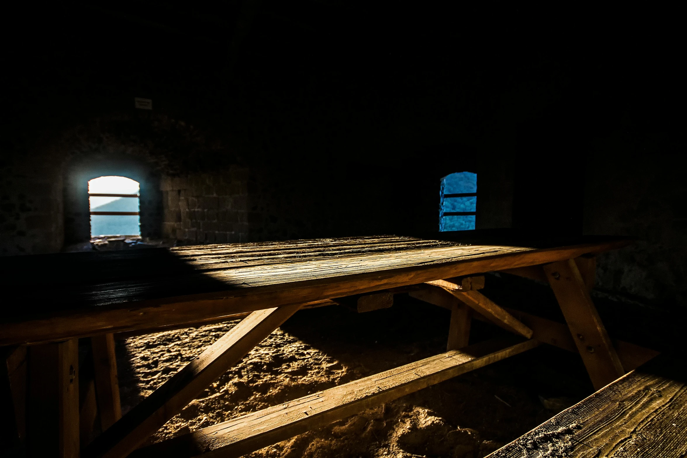 a wooden table in a dark room with a window, light breaks through the roofs, partially covered with dust, benches, medieval photograph