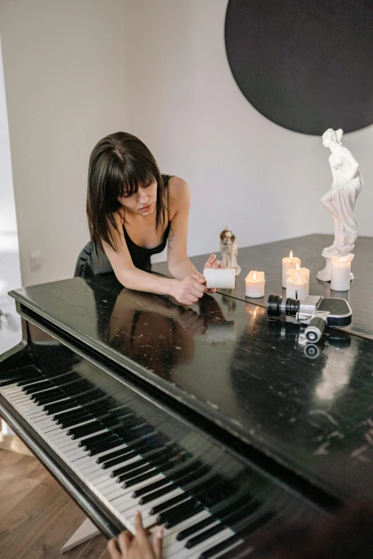 a woman sitting at a piano in a living room, an album cover, by Julia Pishtar, unsplash, on a candle holder, adi granov, making of, full - body artwork