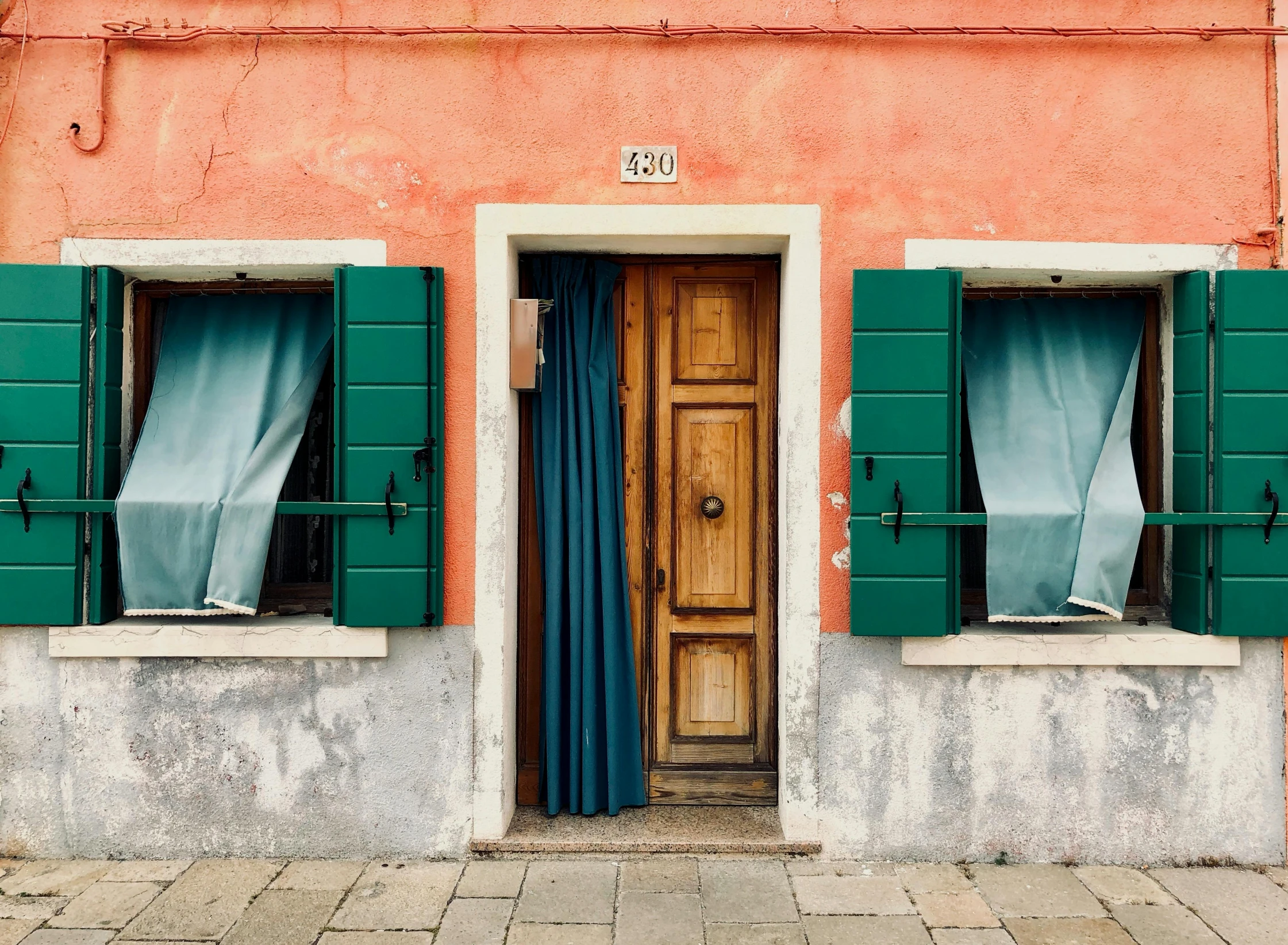 a red building with green shutters and a wooden door, pexels contest winner, visual art, teal orange, venice biennale, awnings, doors to various bedrooms