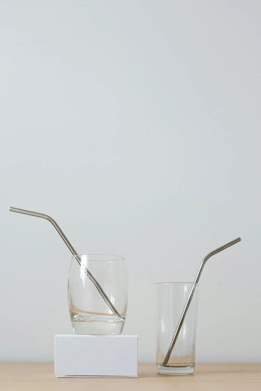 a couple of glasses sitting on top of a wooden table, with a straw, made of brushed steel, hero shot, botanicals