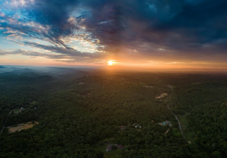 an aerial view of the sun setting over a forested area, unsplash contest winner, hudson river school, gopro photo, panoramic, fan favorite, helicopter view