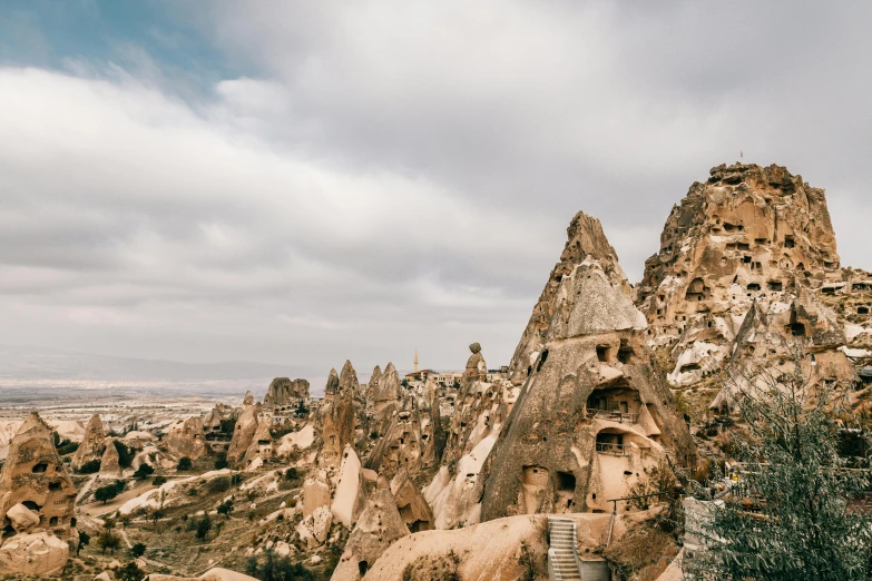 a group of people standing on top of a mountain, trending on pexels, art nouveau, mud and brick houses, turkey, stone grotto in the center, asymmetrical spires