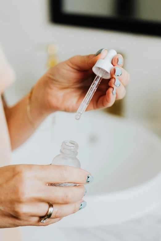 a close up of a person holding a bottle of liquid, by Nicolette Macnamara, pexels, skincare, test tubes, sink, collection product
