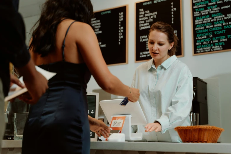 a woman that is standing in front of a counter, reaching out to each other, at checkout, top selection on unsplash, sitting on a mocha-colored table