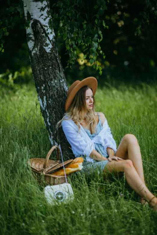 a woman sitting in the grass next to a tree, having a picnic, jovana rikalo, with straw hat, 2019 trending photo