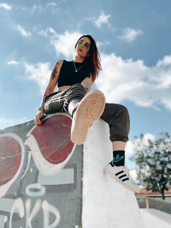 a woman sitting on top of a skateboard ramp, trending on pexels, wearing adidas clothing, cumulus tattoos, profile image, queer woman