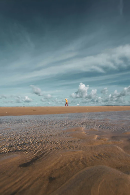 a man flying a kite on top of a sandy beach, inspired by Scarlett Hooft Graafland, unsplash contest winner, minimalism, yellow clouds, wales, astronaut walking, 8 k wide shot