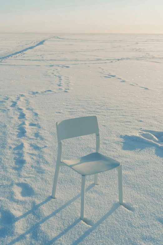 a white chair sitting on top of a snow covered field, inspired by Einar Hakonarson, unsplash, conceptual art, white table, helsinki, hito steyerl, cold colours