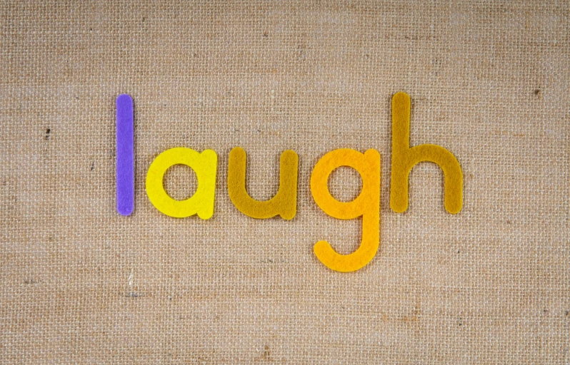 the word laugh spelled out of wooden letters, inspired by Mark English, unsplash, letterism, yellow purple, relaxed. gold background, 🦩🪐🐞👩🏻🦳, rainbow