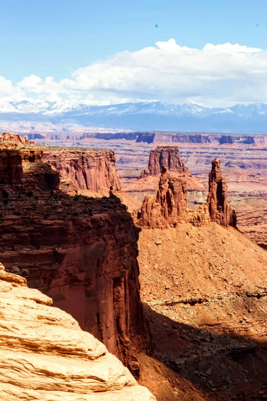 a man standing on top of a cliff next to a canyon, moab, slide show, distant rocky mountains, distant photo