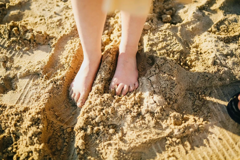 a person standing on top of a sandy beach, barefeet, sandy beige, brown, tan