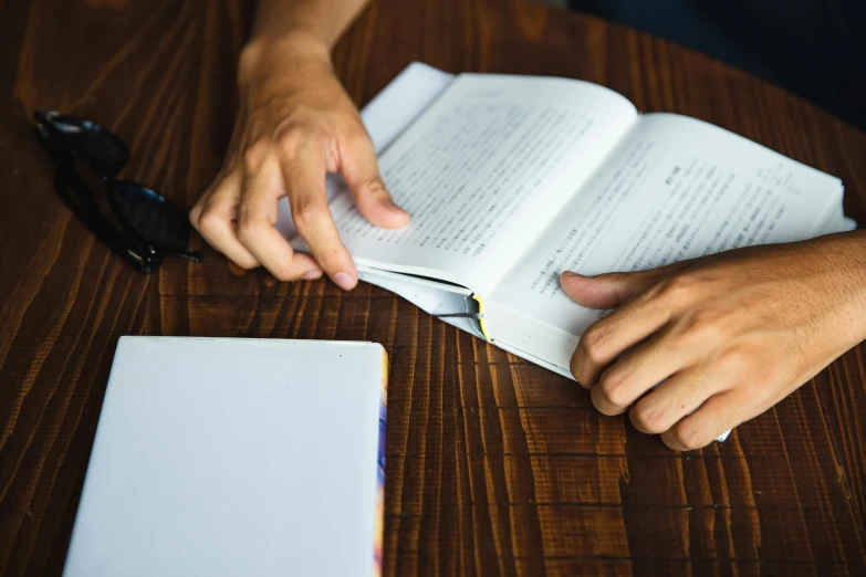 a person sitting at a table reading a book, pexels contest winner, reading engineering book, bending down slightly, woody\'s homework, no - text no - logo