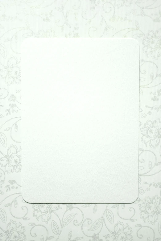 a piece of paper sitting on top of a table, white borders, rounded corners, textured base ; product photos, solid white background
