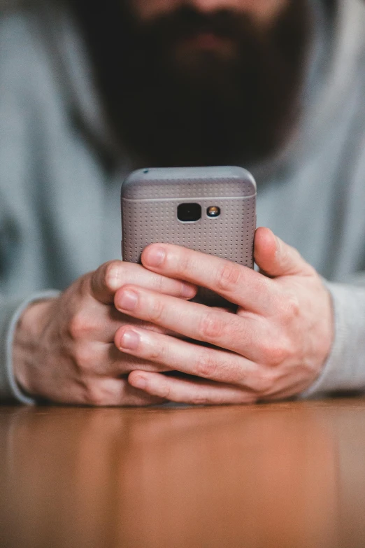 a close up of a person holding a cell phone, by Adam Rex, distant photo, bearded, grey, a quaint