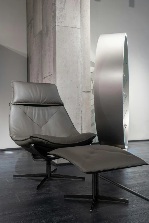 a chair and ottoman in a large room, inspired by Otto Lange, pexels contest winner, conceptual art, steel gray body, pininfarina, blades, leather