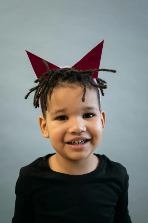 a little boy with a crown on his head, a character portrait, inspired by Jean-Michel Basquiat, pexels contest winner, cat ears and tail, crimson themed, non binary model, toothless