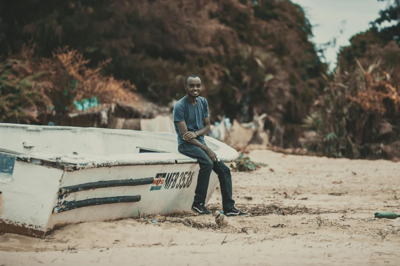 a man sitting on top of a boat on a beach, an album cover, pexels contest winner, emmanuel shiru, grey, high quality picture, sitting on a bench