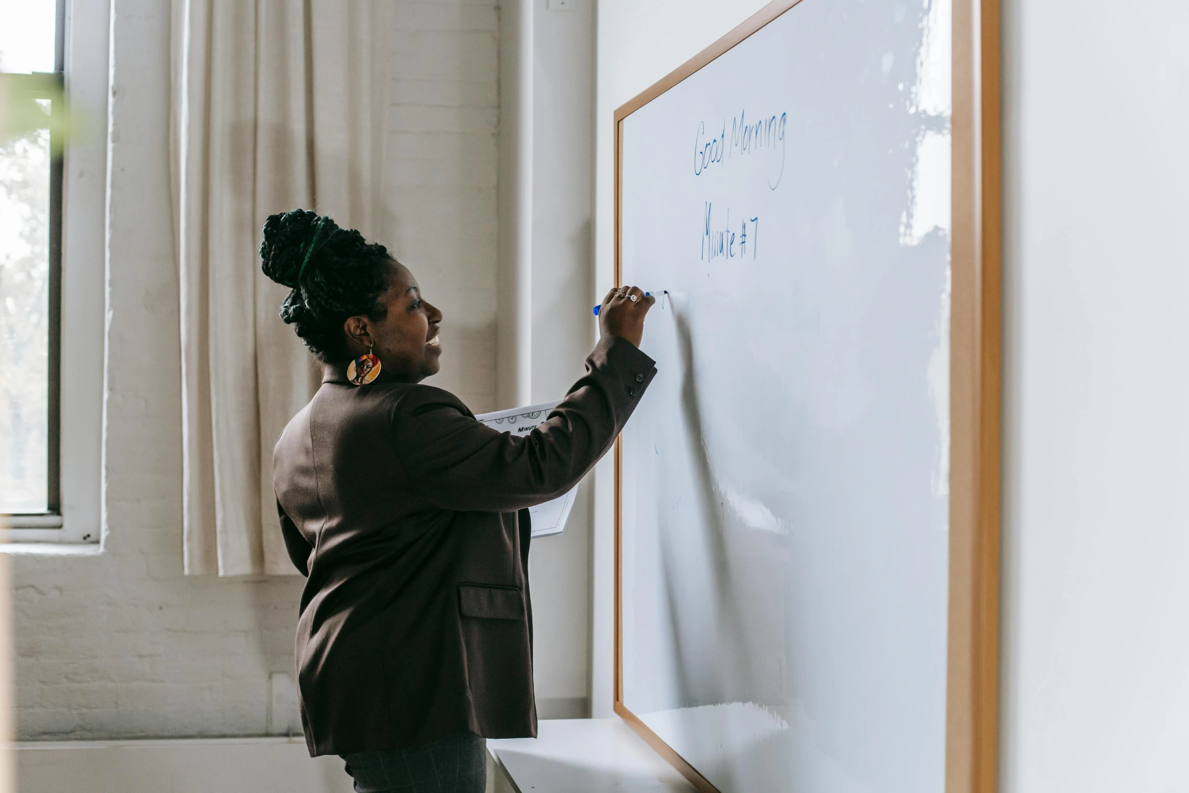 a woman writing on a white board in a room, pexels contest winner, augusta savage, teaching, profile image, background image