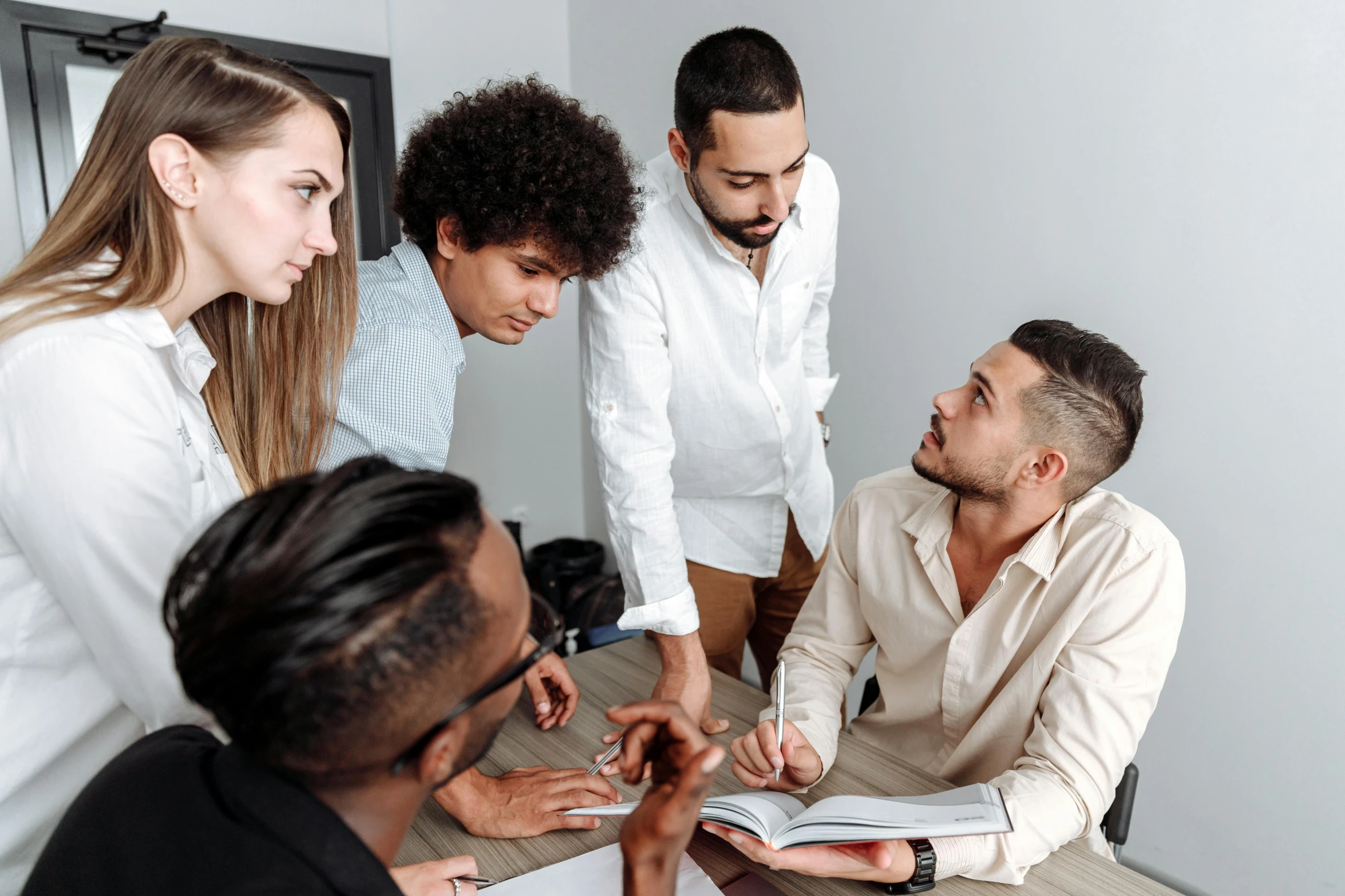 a group of people sitting around a wooden table, on a white table