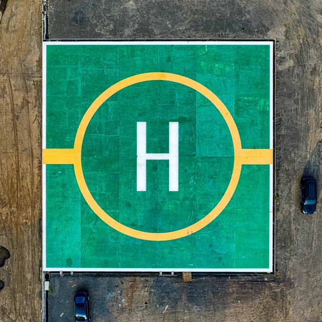 a green and yellow sign sitting on the side of a road, by Brad Holland, happening, dji top down view, helipad, hydrogen. beautiful, hermes