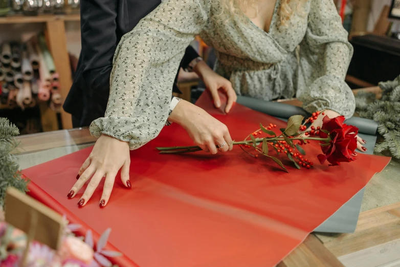 a woman cutting flowers on a red cutting board, pexels contest winner, private press, leather clothes, wearing festive clothing, on a table, woman holding another woman