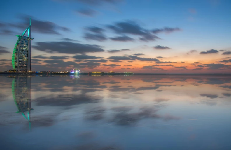 the burjra tower is reflected in the water, pexels contest winner, minimalism, sunset panorama, night sea, long beach background, sunset + hdri