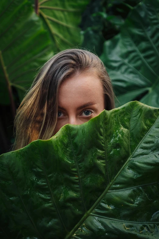 a woman hiding behind a large green leaf, unsplash contest winner, portrait 8 k, multiple stories, 2 0 yo, tourist photo