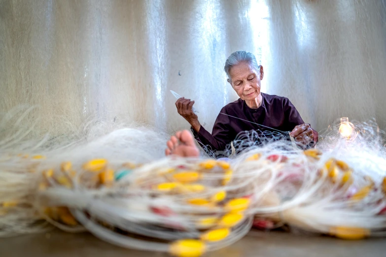 a woman sitting in front of a pile of yarn, a portrait, inspired by Ruth Jên, pexels contest winner, old man doing hard work, made of plastic, netting, made of silk paper