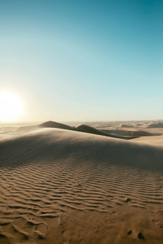 a man riding a surfboard on top of a sandy beach, by Daniel Seghers, trending on unsplash, baroque, mexican desert, 4 k cinematic panoramic view, sun at dawn, craters