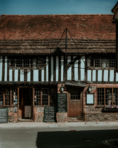 a black and white building sitting on the side of a road, pexels contest winner, arts and crafts movement, medieval tavern, brick building, brown, medieval cottage interior