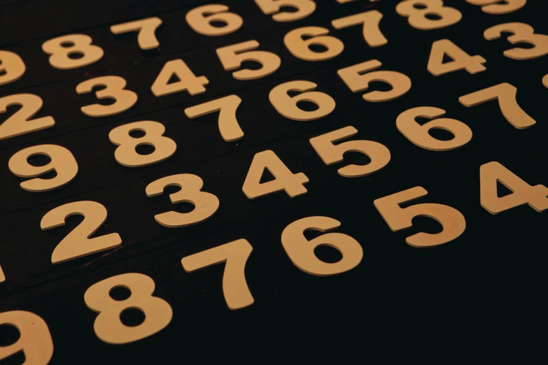a table topped with lots of wooden numbers, unsplash, serial art, black and gold palette, ffffound, profile image, 6