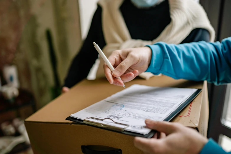 a person sitting at a desk with a pen in their hand, delivering mail, covid, health supporter, cardboard