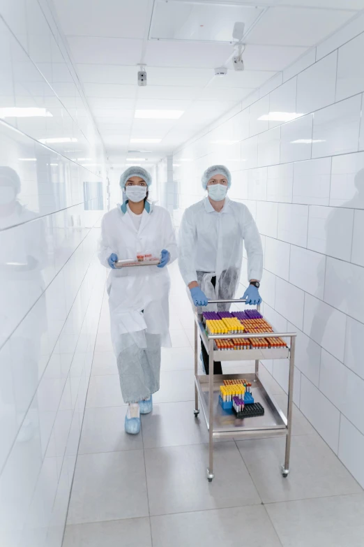 a couple of people that are standing in a room, in a research facility, ready to eat, sterile colours, cart