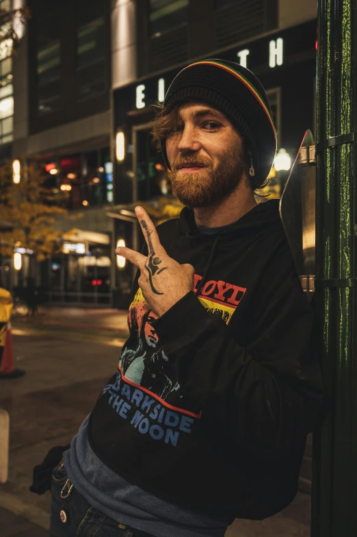 a man standing on a city street at night, a photo, inspired by Cam Sykes, featured on reddit, graffiti, asmongold, giving the middle finger, high quality photo, profile image